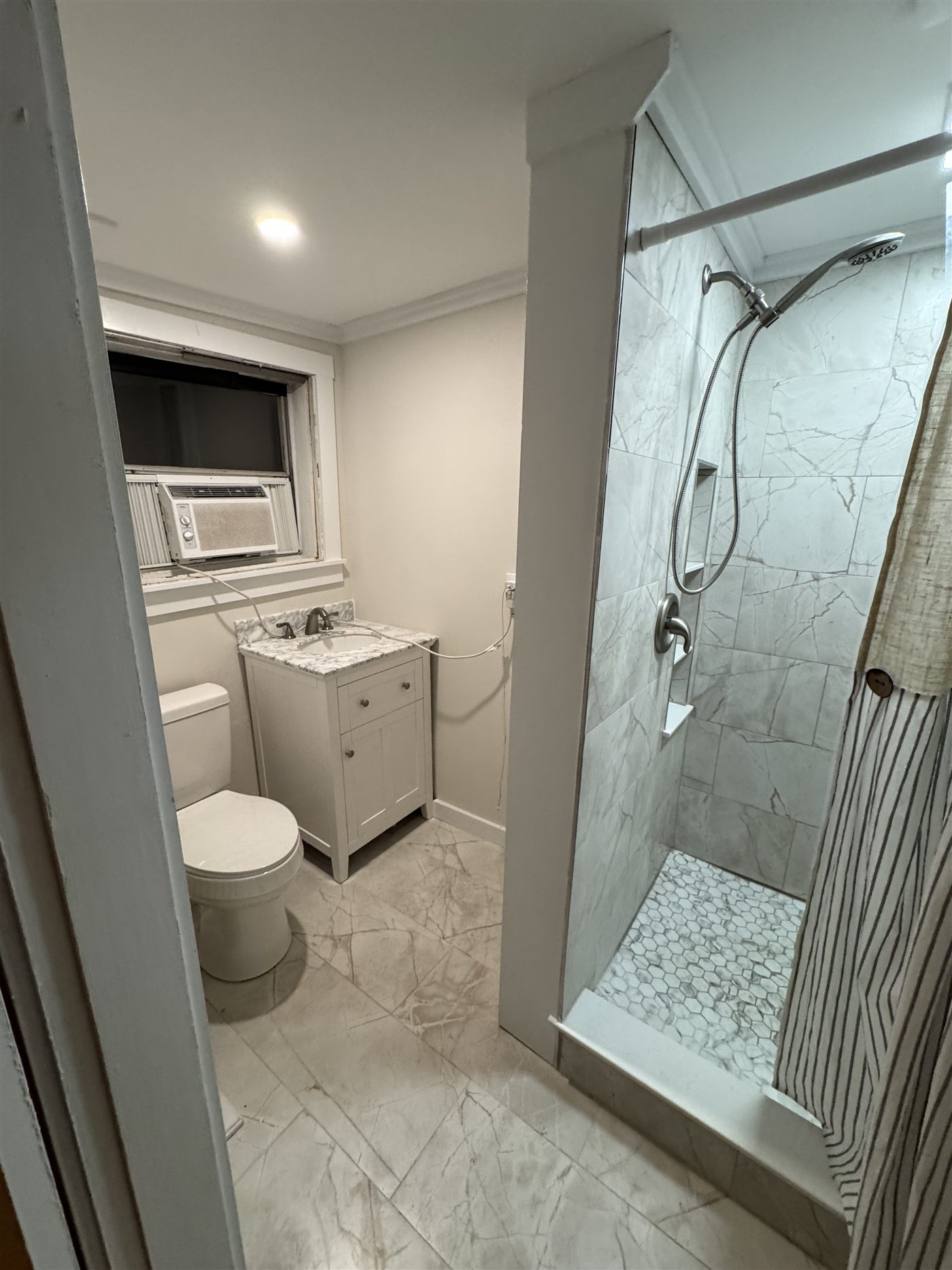 Marble-look shower with hexagon mosaic floor