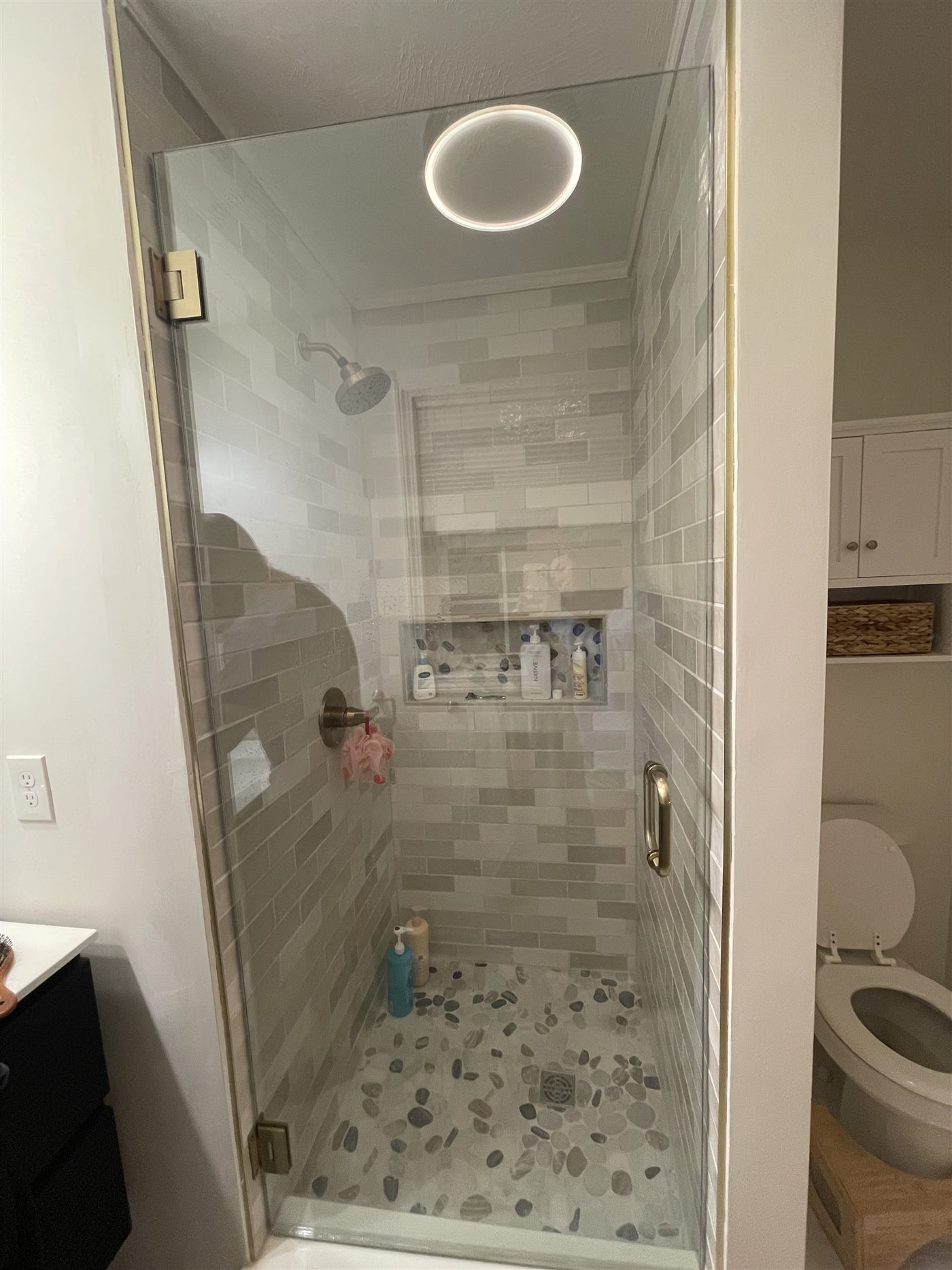 Frameless glass shower with subway tile and pebble floor